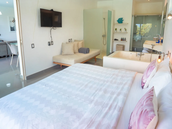 modern hotel suite with king bed, soaking tub, and tv
