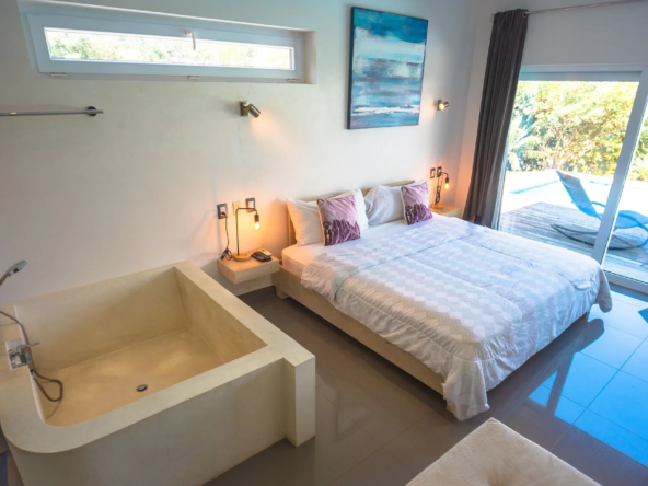 modern master bedroom with soaking tub, king bed, pool access